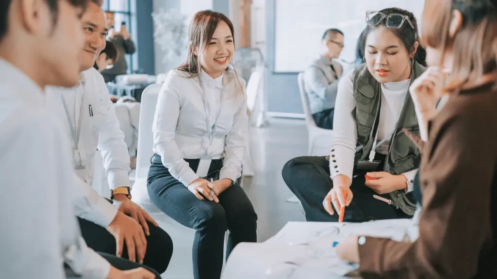 オフィスで若手メンバーが輪になって座り、資料を確認しながら活発に意見交換をしている様子