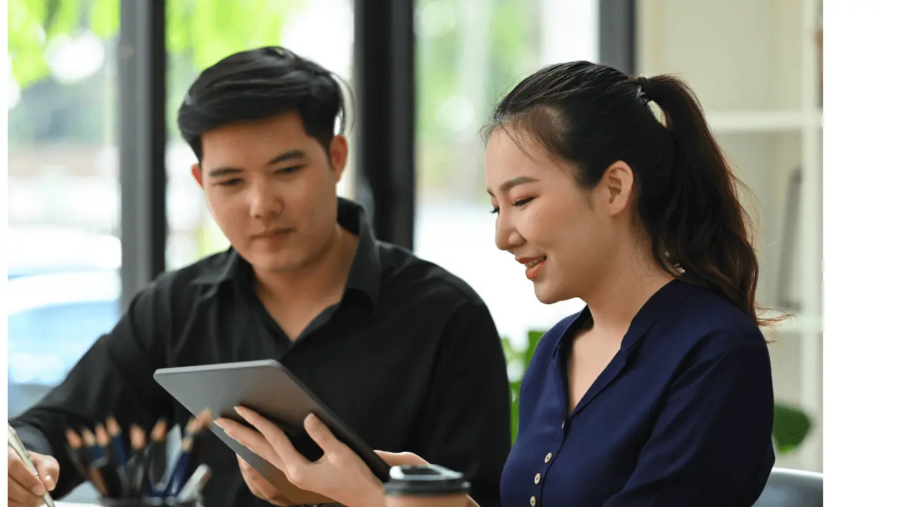 テーブルでタブレットを見ながら話し合う男女のビジネスパーソンの様子